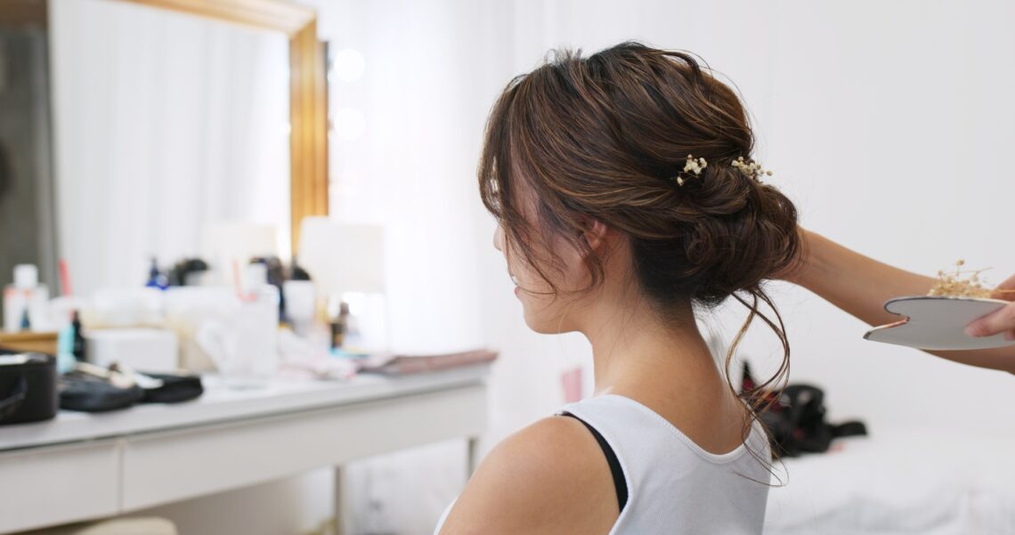 Hairdresser creating a hairstyle for bride in salon