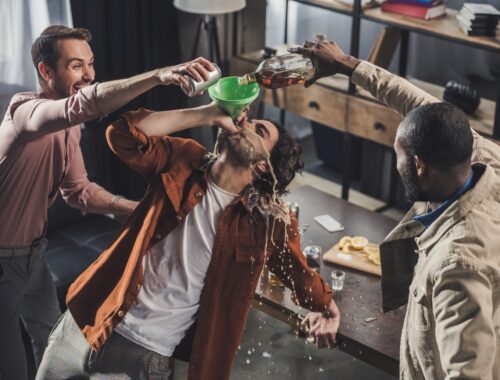 high angle view of man drinking from funnel while friends pouring alcohol beverages