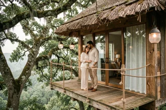 Couple en voyage de noces sur la terrasse suspendue d'une cabane dans les arbres entourée de forêt